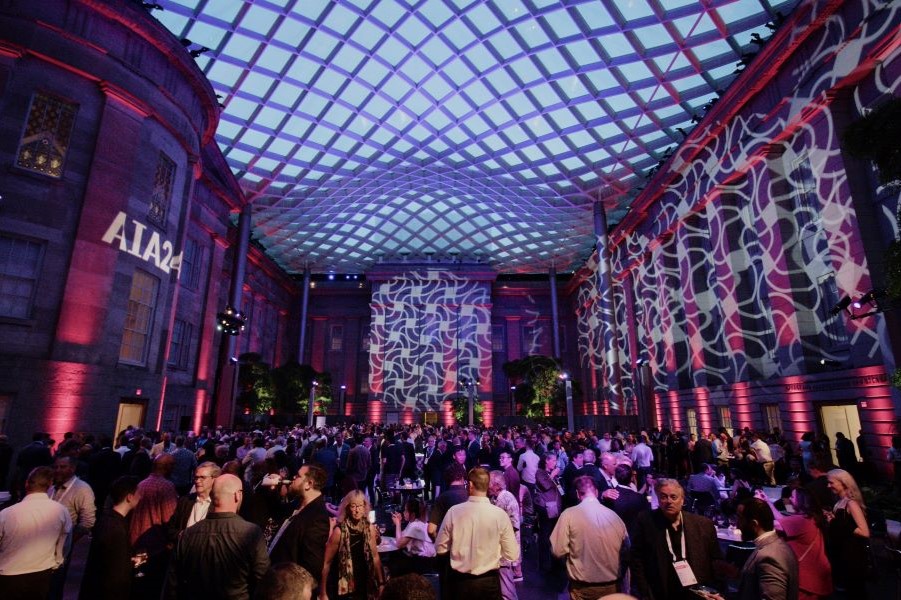 A vibrant event under a stunning glass canopy with dynamic lighting and a lively crowd.