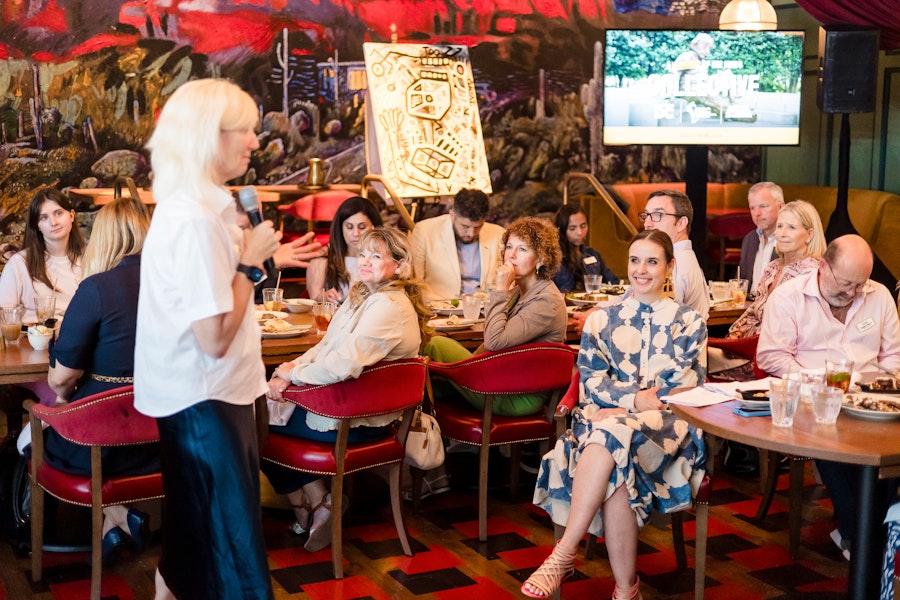 A dynamic speaker addresses an attentive and diverse audience in a colorful and artistic venue.