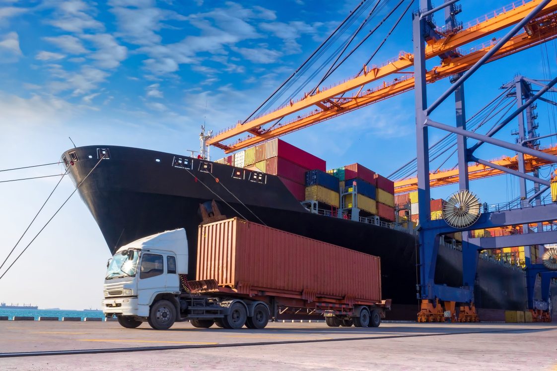 cargo shipped docked at port unloading containers onto trucks