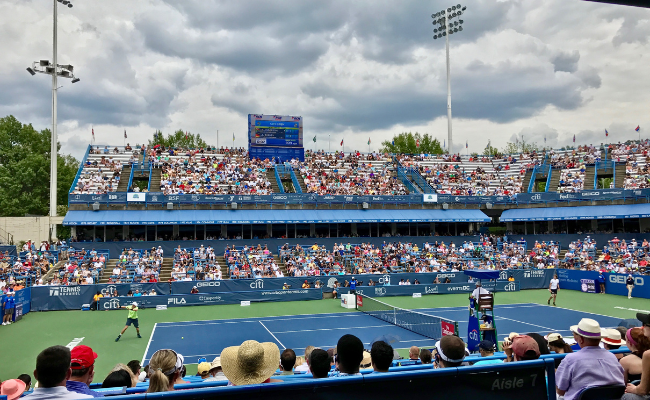 A tennis match in progress, featuring two players competing on a court with a net and spectators in the background.