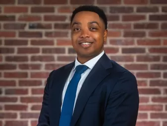 A man in a suit smiles for a professional headshot. 