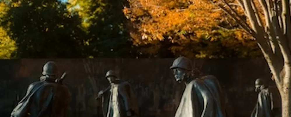 Several figures from the Korean War Veterans Memorial with autumn trees.